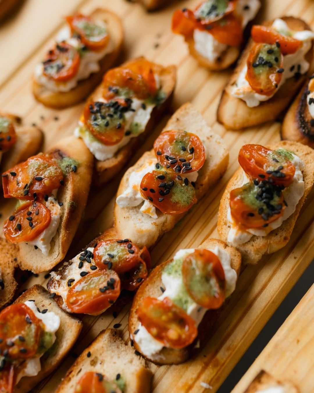 Bruschetta with whipped cheese, roasted cherry tomatoes and black sesame.
