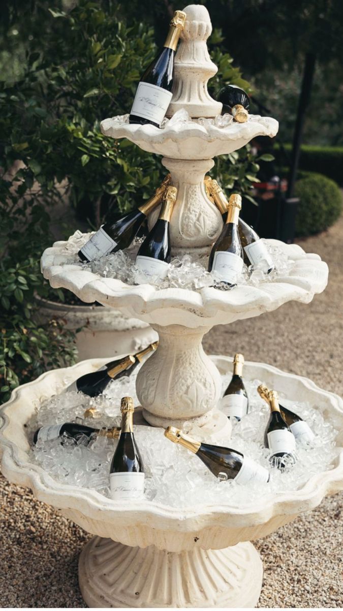 Bottles of sparkling wine on ice in a tiered stone fountain.